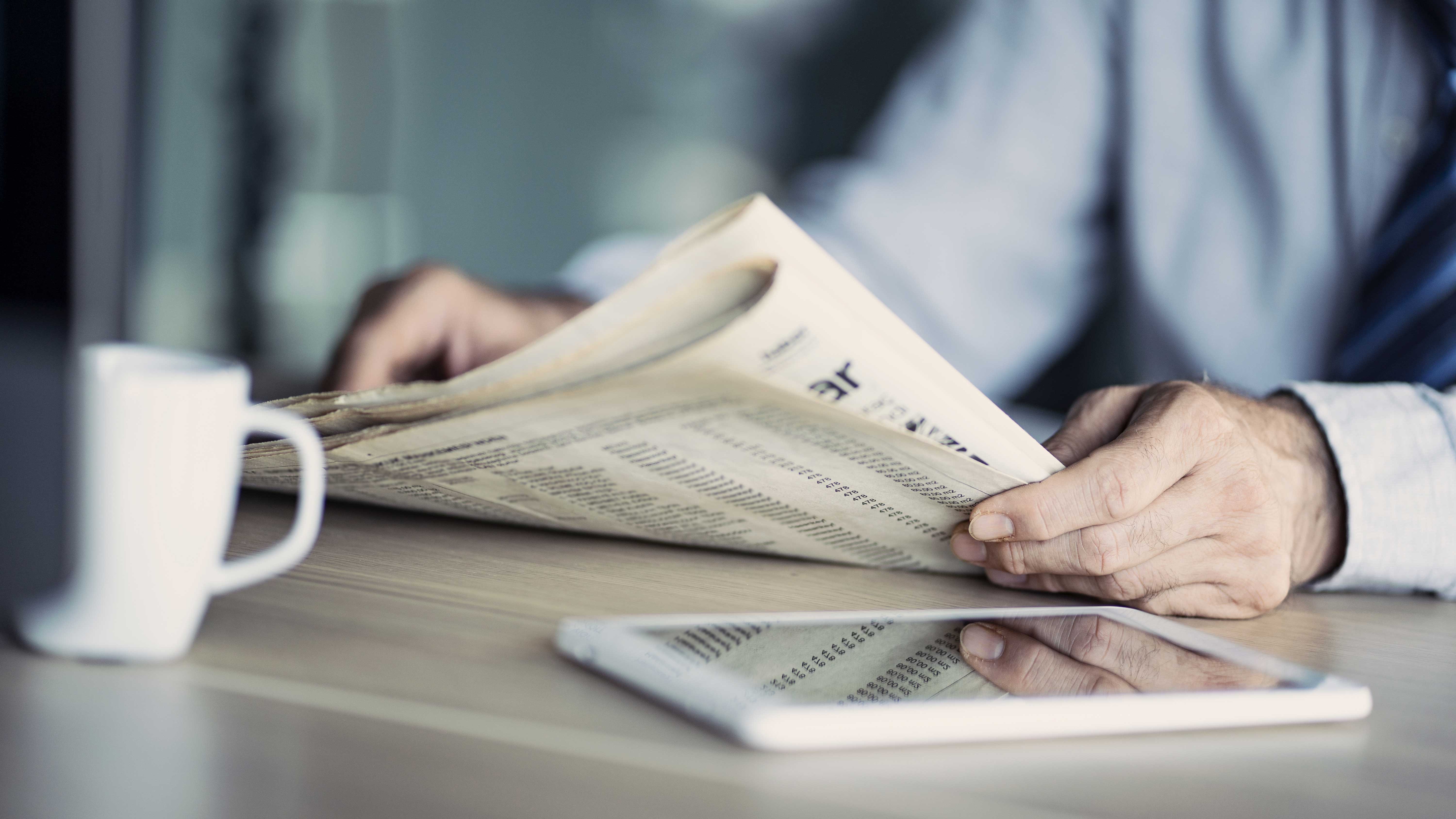 テーブルの上の新聞を読むビジネスマン